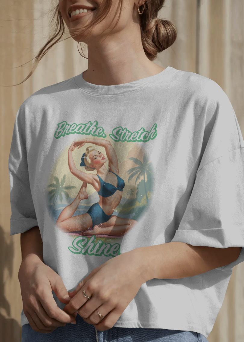 Person wearing a t-shirt with a graphic design and text 'Breathe. Stretch. Shine.'