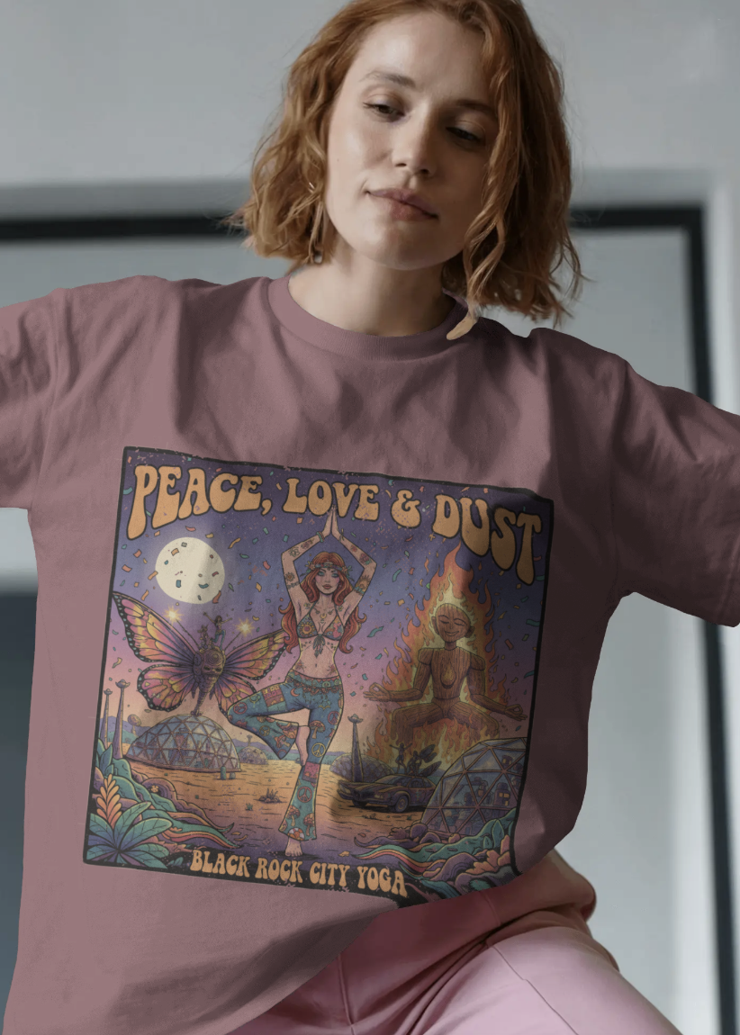 Person wearing a t-shirt with a graphic design of a person in a yoga pose, butterfly, and text 'Peace, Love & Dust' with a plain background.